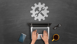 New guidance icon on blackboard with close up of hands tapping on a laptop