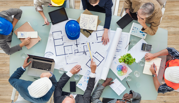 A group sitting around a table reviews construction plans