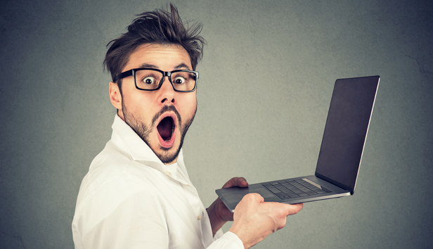 A surprised man holding a laptop