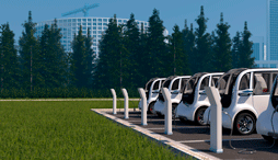 Shows a fleet of mid-sized electric vehicles being charged at a public charging station