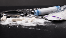 A close up of handcuffs set against illegal drugs