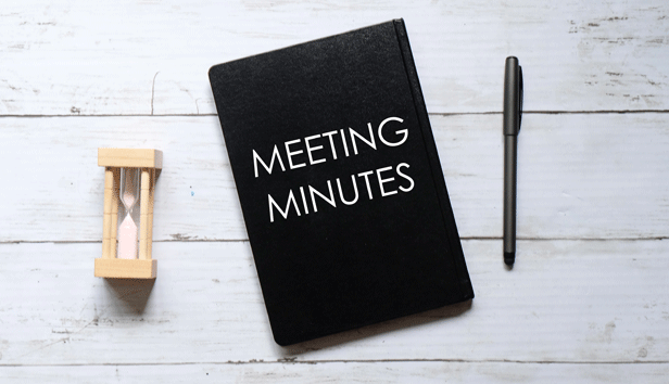A notebook for meeting minutes, lies between a pen and an hourglass