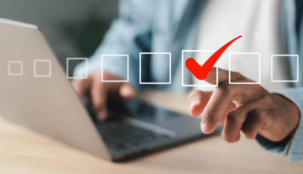Close up of person's hand checking off a square box on virtual interface while working on a laptop
