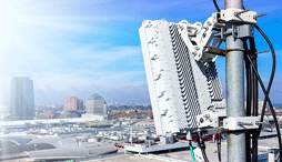 Close up of a small cell wireless module on a utility pole against the backdrop of a city