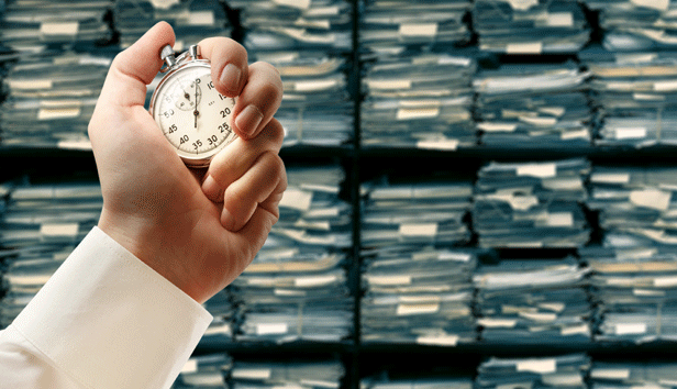 Hand holding stopwatch against a background of shelves filled with files