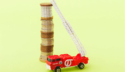 The ladder of a toy firetruck leans against a tall stack of coins