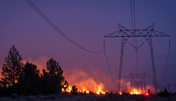 Wildfire under an electrical transmission line in a forested area