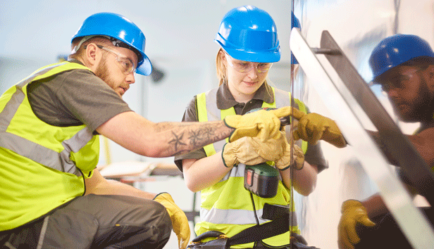 Female apprentice carpenter installs handrails while colleague advises her