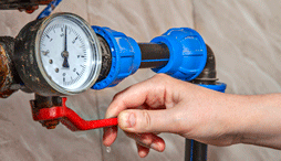 Close up of a hand turning off a main water valve