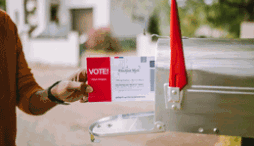 A voter putting their ballot into a mailbox