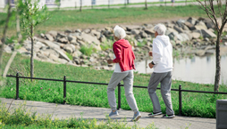 Active senior couple running outdoors in park along lake