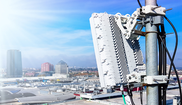Close up of a small cell wireless module on a utility pole against the backdrop of a city