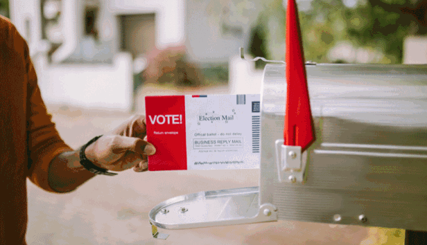 A voter putting their ballot into a mailbox