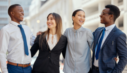 4 smiling young professionals standing arm in arm
