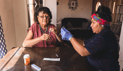 An EMS personnel helping an older resident with medication in a home-based setting
