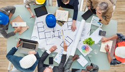 A group sitting around a table reviews construction plans