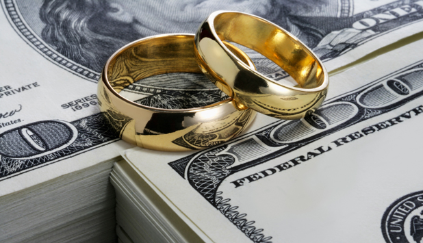 Two gold wedding rings on a stack of US $100 dollar bills