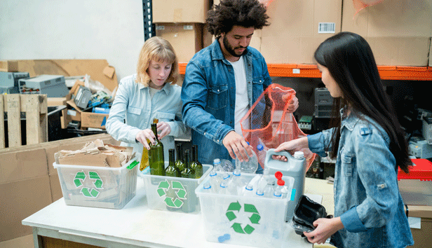 An image of 3 people at a recycling center sorting out types of recycled material