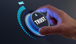 a hand turning a dial to maximum 'trust' 