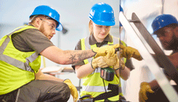 Female apprentice carpenter installs handrails while colleague advises her