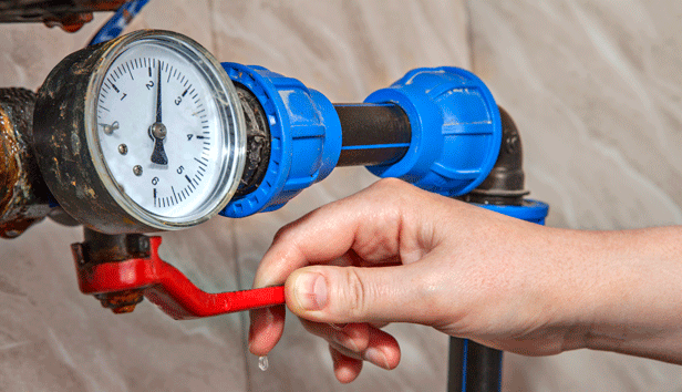 Close up of a hand turning off a main water valve